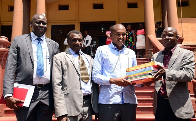  aniel sinde  hands over a copy of some of the books kept the national heritage to the minister of gender labor and social development rank umwebazehoto by hoto by ddie sejjoba