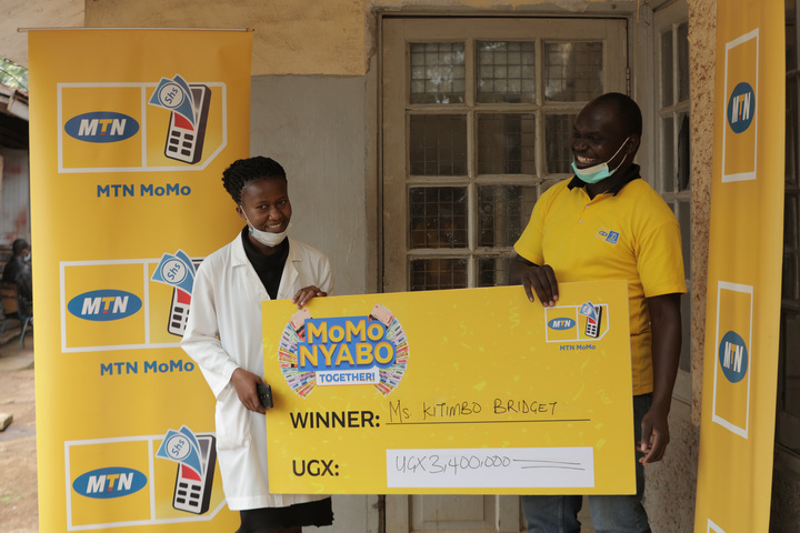 MTN's Emmanuel Thoryek (right) presents Bridget Kitimbo's dummy cheque. Her money was sent directly to her phone and that of her beneficiary