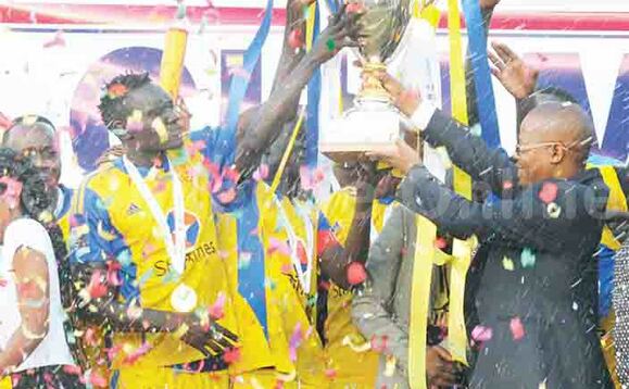 Pulezidenti wa FUFA, Moses Magogo ng’akwasa abazannyi ba KCCA ekikopo kya sizoni 2015/16. Pulezidenti wa FUFA, Moses Magogo ng’akwasa abazannyi ba KCCA ekikopo kya sizoni 2015/16.