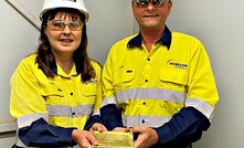  Horizon Minerals MD Jon Price holds a gold bar with a staff member.