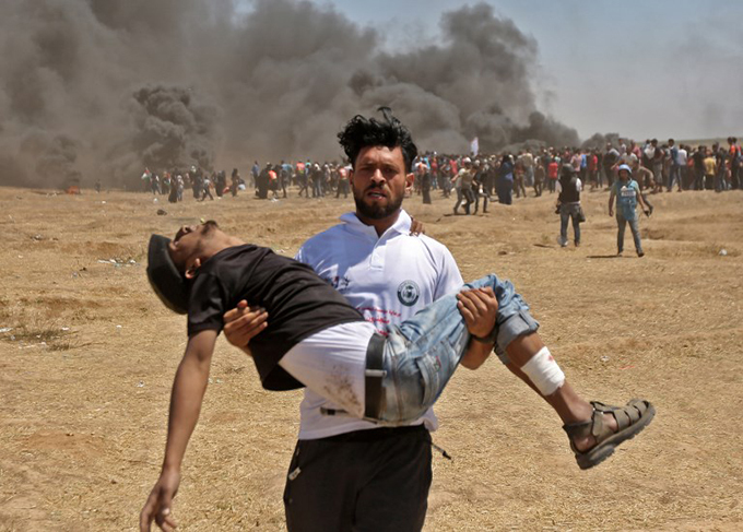  alestinian carries an injured protester during clashes with sraeli forces near the border between the aza strip and srael east of aza ity during a demonstration on the day of the  embassy move to erusalem  hoto