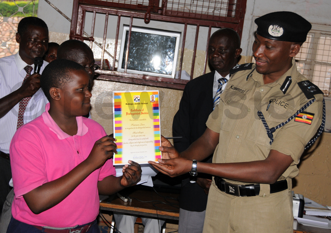 utgoing abojja unior chool head prefect ason sentomero receives a certificate from ndrew aweesi in ecember 2013 hoto by icholas ajoba
