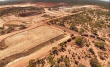 First road trains loading ore with open pit operations in the background.