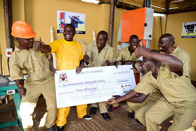  anjankumbi furnituire  members pose with a dummy cheque handed to them by resident oweri useveni  at ajankumbi  along ntebbe oad on ednesday  hoto by ennedy ryema