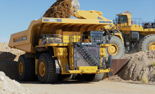 A Komatsu 980E haul truck being loaded by a wheel loader