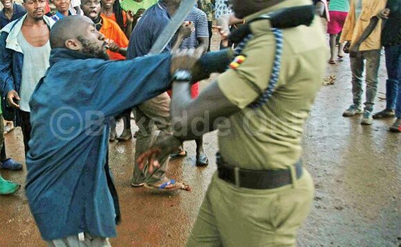 Omu ku basuubuzi ng’ayolekezza Kasembeza ekiso okumutema. Omu ku basuubuzi ng’ayolekezza Kasembeza ekiso okumutema.