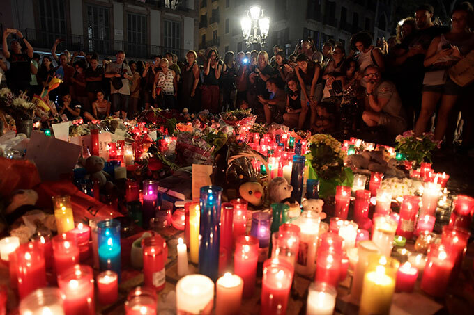  eople stand next to flowers candles and other items set up on the as amblas boulevard in arcelona as they pay tribute to the victims of the arcelona attack a day after a van ploughed into the crowd killing 14 persons and injuring over 100 on ugust 18 2017   hoto  avier oriano