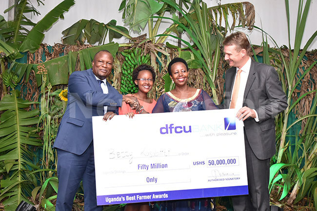 he etherlands mbassador to ganda enk an akker right and fcus managing director athias atamba left hand over a cheque to etty bazira thirdleft  the overall winner of est armers competition as her daughter atasha bazira 2nd left looks on