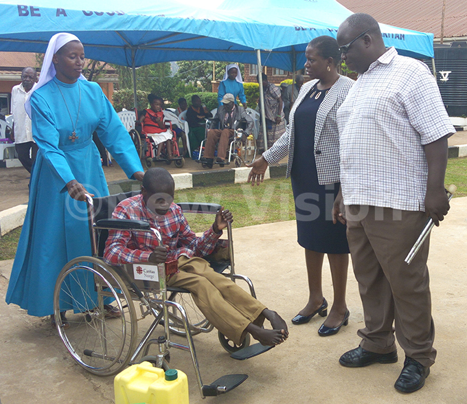   ister ildred bitegeka helps one of the patients with disability as the qual pportunity ommission hairman ylvia uwebwa tambi and his commissioner ulius amya look on