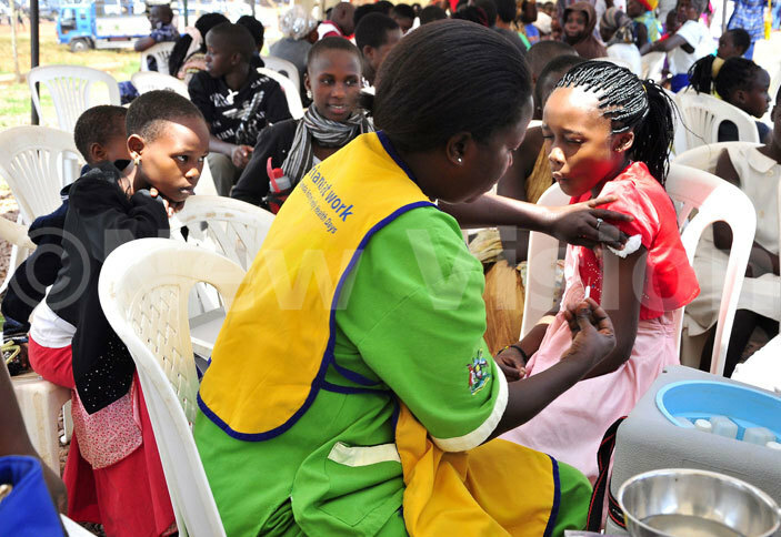   nurse from itebi health center lavia akalembe immunizes hristella iiza as other children look on 