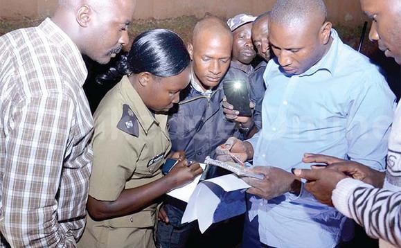 Abaserikale ba poliisi nga bakebera ebiwandiiko bya Bright Turyatunga omujaasi wa SFC. Abaserikale ba poliisi nga bakebera ebiwandiiko bya Bright Turyatunga omujaasi wa SFC.