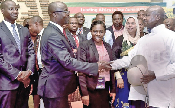 Pulezidenti Museveni ng’ayanirizibwa mu lukuhhaana olukwata ku tekinologiya ow’omulembe mu by’omusolo. Ku kkono ye Mukiibi akola ng’akulira URA. Pulezidenti Museveni ng’ayanirizibwa mu lukuhhaana olukwata ku tekinologiya ow’omulembe mu by’omusolo. Ku kkono ye Mukiibi akola ng’akulira URA.