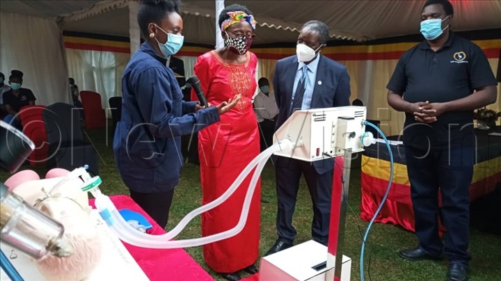 Pauline Korukundo the vehicle Integration Manager at KMC demonstrates to the Minister of Health how the how the medical ventilator works. 