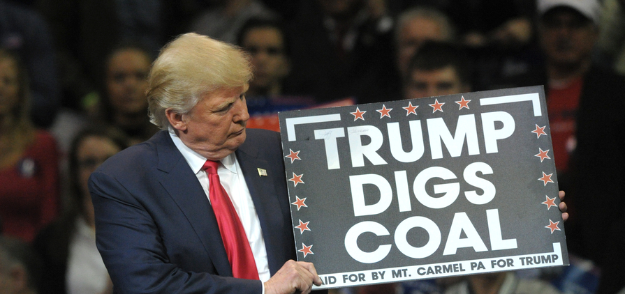 Donald Trump holds a 'Trump Digs Coal' sign during a rally in 2016.