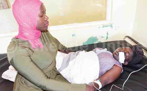 Maama w’abaana Namubiru ng’ali ku kitanda. Maama w’abaana Namubiru ng’ali ku kitanda.