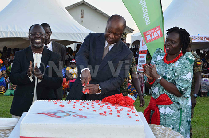  he hairman of the oard of irectors at traight alk oundation obby uhumuza left  and the organisations xecutive irector usan jok right cheer as abaka utebi cuts a cake in celebration of the 25th anniversary of the organisation at alaama chool for the lind uluga in ukono district on unday ctober 7 2018 hoto by athias azinga