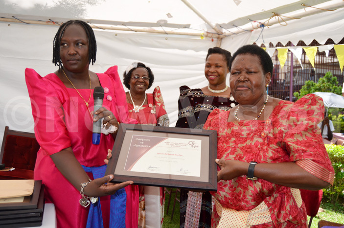  etired ambassador ernadette lowo right receives a recognition award from seppuya left as ikomeko second left and enywa look on 