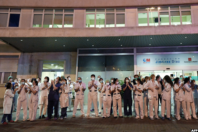  ealthcare workers dealing with the new coronavirus crisis applaud in return as they are cheered on by people outside the undacion imenez iaz hospital in adrid