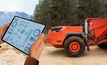 Man controls autonomous mining truck using digital tablet.