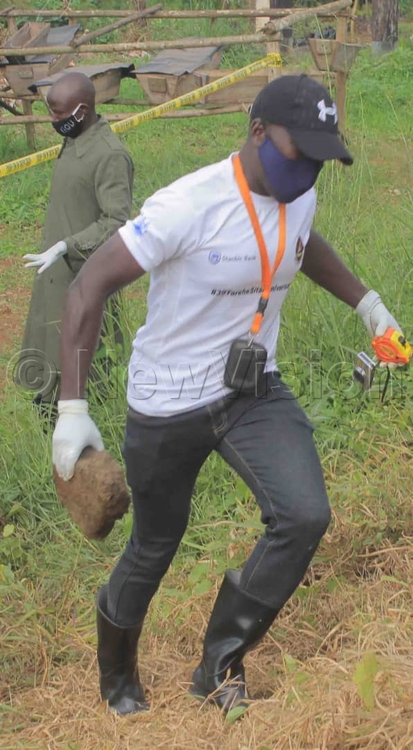 A detective carrying a stone that was used to kill Kulubya. Photos by Ben Wasswa Ssentongo