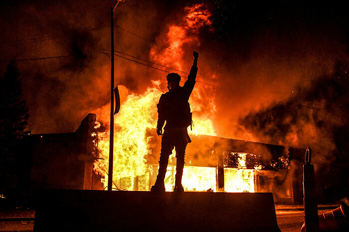 protester reacts standing in front of a burning building set on fire during a demonstration in inneapolis innesota on ay 29 2020 over the death of eorge loyd a black man who died after a white policeman kneeled on his neck for several minutes hoto by handan