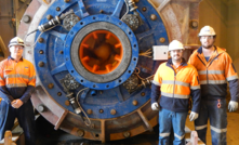 Weir Minerals employees stand next to a Warman pump equipped with throatbush adjustment technology