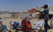 An artisanal miner with no safety equipment feeds a crusher with ore before using hazardous mercury to extract gold. 