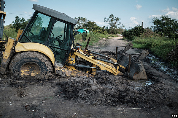   backhoe stuck in mud sits on a road after the area was hit and isolated by yclone dai in staquinha