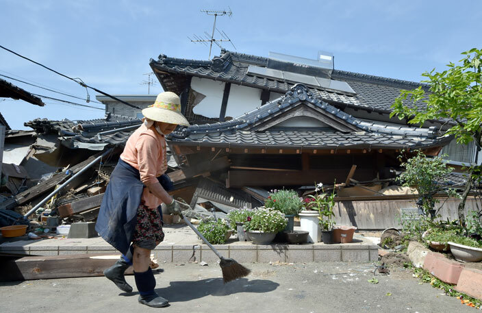  woman cleans up in front of her collapsed house in the town of ashiki umamoto prefecture on pril 15 2016  