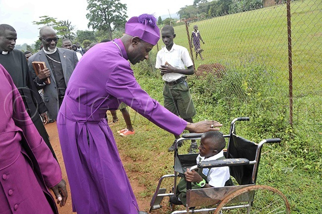  rchbishop aziimba blessing a child with disability illian akisanja who is in rimary ive at nternational eeds chool