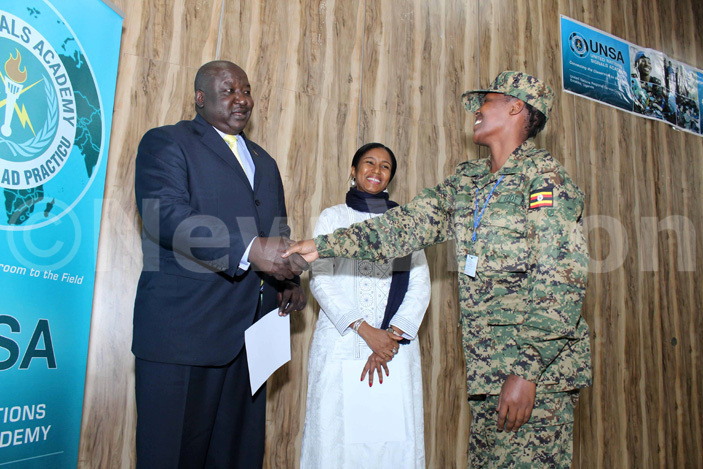  orrine kullo a  officer receives a certificate from state minister for foreign affairs enry ryem while  egional ervice entre  chief afia oly looks on  during the graduation ceremony