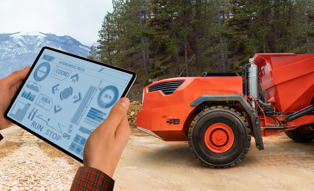 Man controls autonomous mining truck using digital tablet.