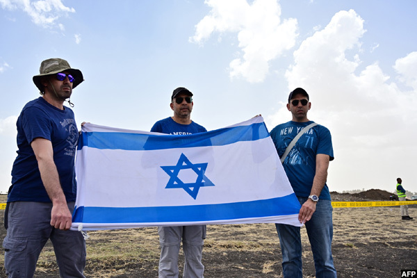  ir arush  with his nephews oam  and oshi relatives of the sraeli victim himon aniely hold the sraeli flag at the crash site
