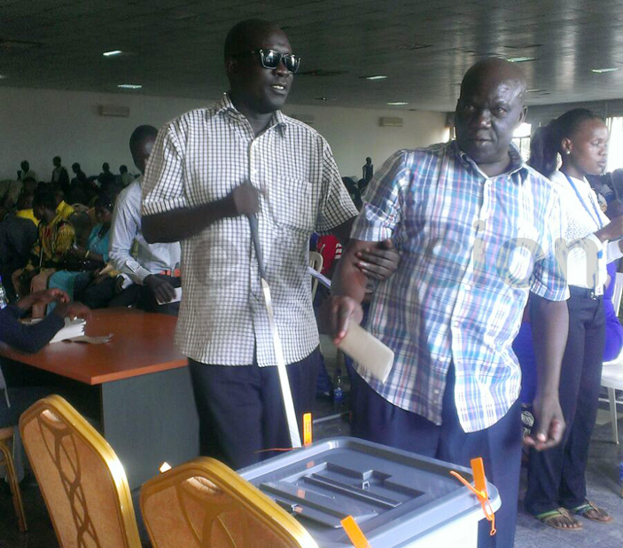   blind man is assisted in casting his vote hoto by iriam amutebi