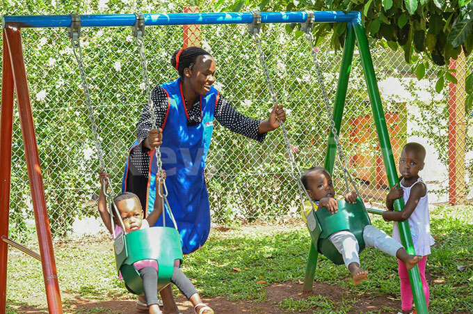   preschool teacher helps out the children as they play with the swings hoto by ictoria ampala