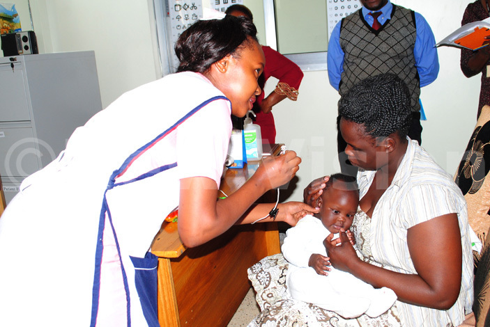   nurse at ntebbe eneral ospital innie abukeera screens baby oan wanga for ubella erman easles while other gnes dezo right looks on during the arly ntervention roject official launch at ntebbe eneral ospital 