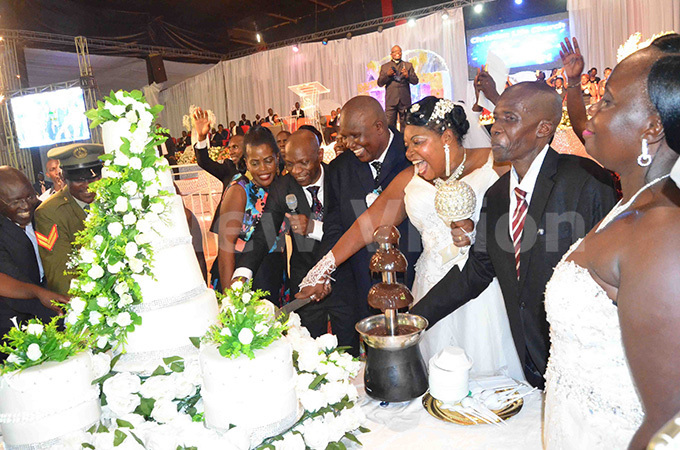  ome of the newly wed couples cut a cake with astor ackson sennyonga and his wife ve 