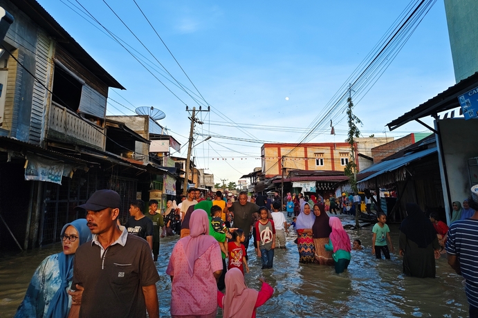Aceh, Indonesia - November 25, 2025: Flooded neighbourhood market with residents navigating the high water.