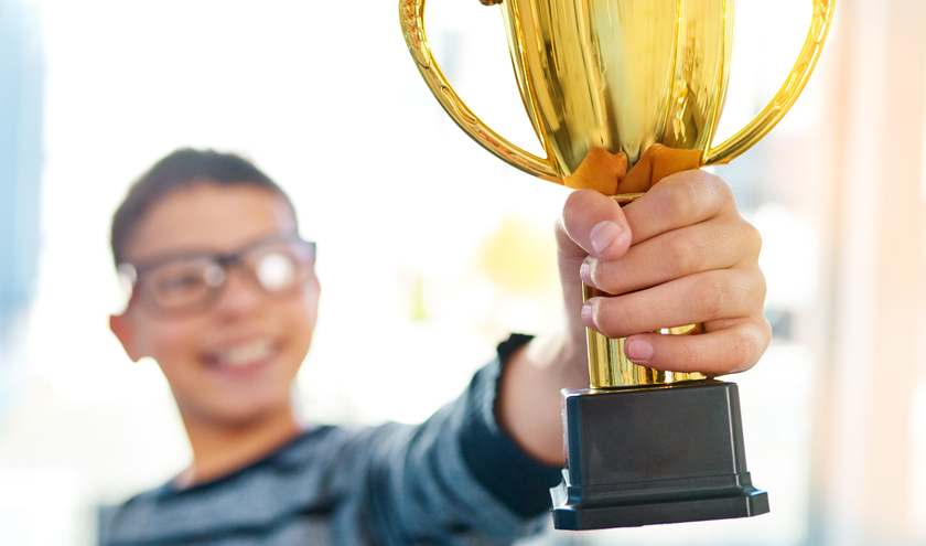 Child holding trophy    © PeopleImages.com – Yuri A / shutterstock
