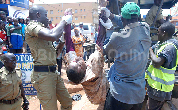 Omuvubuka nga bamussa ku kabangali ya Poliisi okumutwala e Mulago mu ddwaaliro Omuvubuka nga bamussa ku kabangali ya Poliisi okumutwala e Mulago mu ddwaaliro