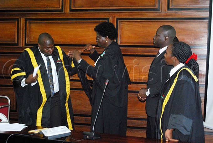  iriam kello yo the uganda oad hief agistratecenter dressing bubaker awalya left the newly elected ampala apital ity uthority  speaker with his official gown as other council members look on 