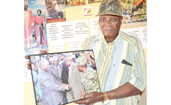 Ssennyondo ng'akutte ekifaananyi ekyamukubwa nga Kabaka amukwata mu ngalo. Ssennyondo ng'akutte ekifaananyi ekyamukubwa nga Kabaka amukwata mu ngalo.