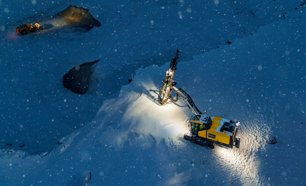 Aerial shot of an Epiroc SmartROC T40 drilling on a dark and snowy night in Sweden.