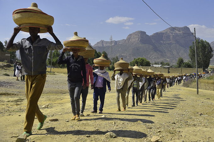 thiopian men carry traditional handwoven food baskets on their heads as they walk ceremoniously to a reconciliation meeting in the rob district in northern thiopia near the border with ritrea  hoto