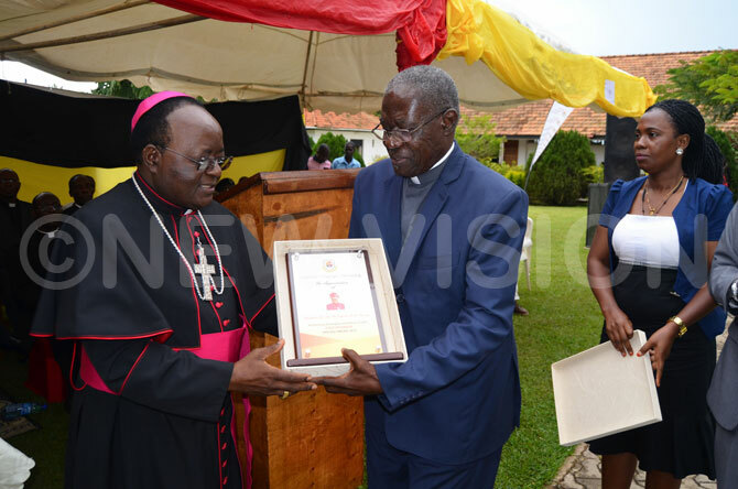  rchbishop wanga receiving a present from aviiri during the 24th anniversary of ganda artyrs niversity kozi on ednesday