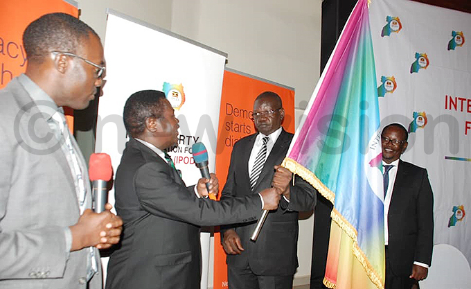  president orbert ao hands over the  flag to s atrick muriat hoto by imon eter umwine