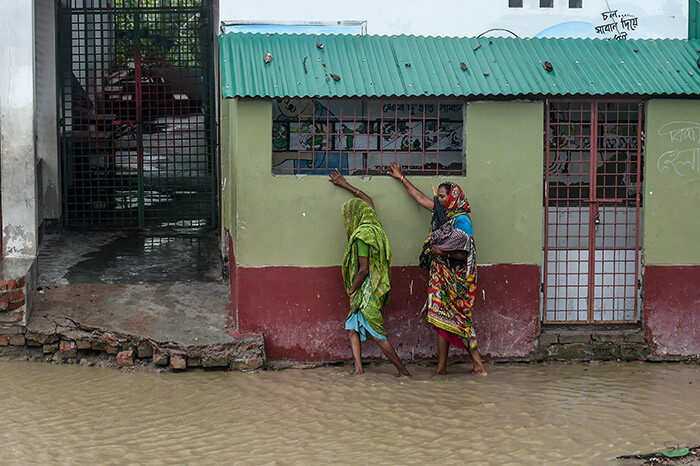  esidents walk along a house on a flooded street heading to a shelter ahead of the expected landfall of cyclone mphan in acope of hulna district on ay 20 2020 hoto by unir uz aman  