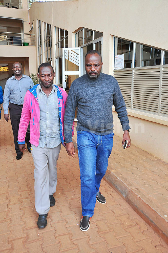  eft to ight usa alugembe  the impersonator being escorted by aptain erman achemba after interrogation hoto by uliet asirye