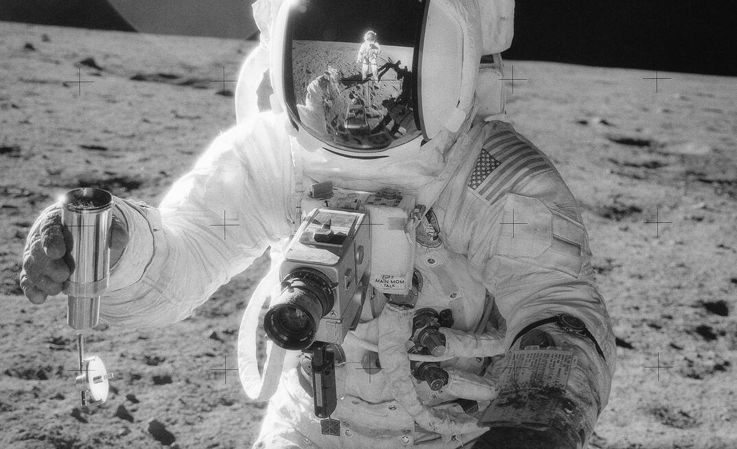 Apollo 12 astronaut holding a container of lunar soil