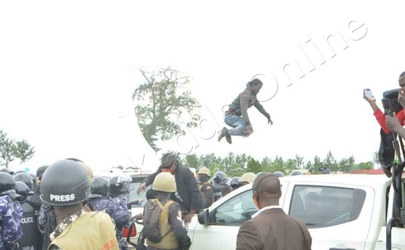 Omuwagizi wa NUP ng'abuuka ku mmotoka ya Bobi Wine okuwona abapoliisi okumukwata. Omuwagizi wa NUP ng'abuuka ku mmotoka ya Bobi Wine okuwona abapoliisi okumukwata.